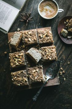 several pieces of cake sitting on top of a wooden cutting board next to a cup of coffee