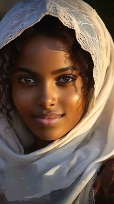 a woman wearing a white shawl and head scarf with her eyes wide open, looking at the camera