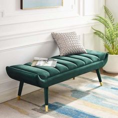 a green bench sitting on top of a rug next to a potted plant