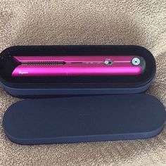 a pink hair straightener sitting on top of a black case next to a brown carpet