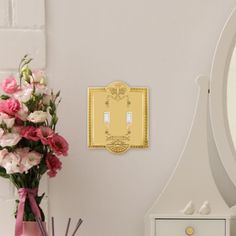 there is a vase with flowers next to a mirror and a light switch on the wall