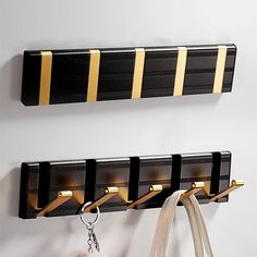 two black and gold striped coat racks with key hooks on them, hanging from the wall