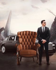 a man in a suit standing next to a car and a brown leather chair with an armrest