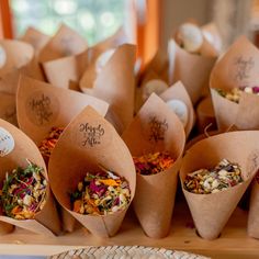 there are many different types of flowers in the paper cones on the table with labels