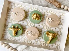 four decorated cookies in the shape of giraffes with gold decorations on them