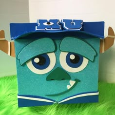 an origami monster with horns and eyes on top of a green fuzzy surface