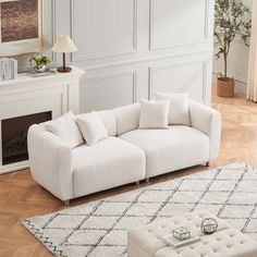 a living room with white furniture and wood flooring, including a large rug on the floor