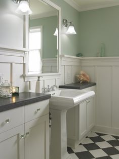 a bathroom with checkered flooring and white cabinets, two sinks in the center