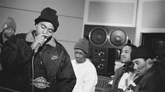 a group of young men sitting around each other in front of a recording studio microphone