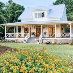 a white house with yellow flowers in the front yard