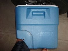 a person holding a blue and white cooler in their hand next to a motorcycle tire