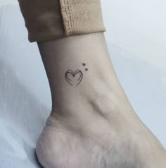 a small heart tattoo on the ankle is shown in black ink, and it has two hearts