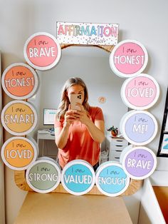 a woman taking a selfie in front of a mirror with words written on it