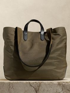 Rugged and minimalist, this canvas and buffalo leather tote bag is designed with space to spare thanks to a large, uninterrupted interior with a snap closure.  We added one zip pocket inside to keep track of small items like phones and keys, as well as two sets of straps so you can carry by hand or on the shoulder.  Snap top closure.  One interior zip pocket.  Buffalo leather straps, Fully lined.  Height: 15. 5" Top width: 20. 5" Bottom width: 15. 75" Depth: 6. 5" Shoulder strap drop: 13. 5" Nylon Tote Bag, Mom Tote Bag, Suede Tote Bag, Best Tote Bags, Simple Tote, Bag Mockup, Nylon Tote Bags, Crossbody Tote Bag, Nylon Tote