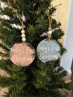 two wooden ornaments hanging from the top of a christmas tree, one saying baby's first christmas