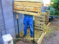 a man standing in front of a pile of hay holding onto a wooden pallet