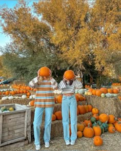 two people standing next to each other in front of hay bales filled with pumpkins