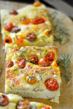 slices of pizza with tomatoes and herbs on a cutting board