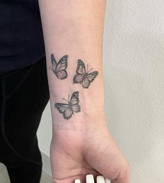 a woman's wrist with three butterflies tattooed on the left side of her arm