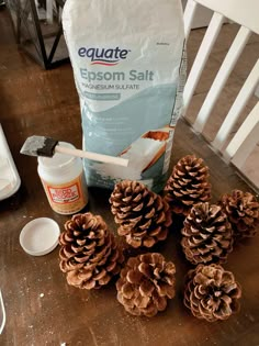 some pine cones sitting on top of a wooden table next to a bag of epsom salt