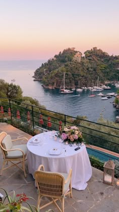 an outdoor dining area overlooking the water with tables and chairs set up for two people