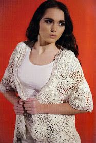 a woman wearing a white crochet cardigan standing in front of a red background