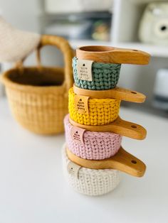 a stack of knitted objects sitting on top of a white table next to a basket