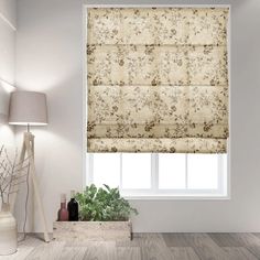 a white room with a window covered in roman blind shades and a potted plant next to the window