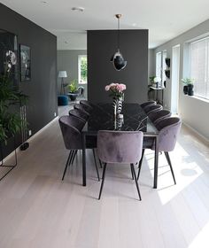 a dining room table with purple chairs and flowers in vases on the top of it