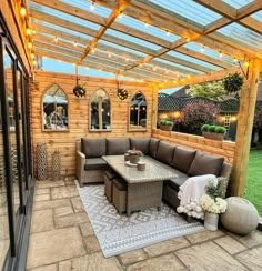 an outdoor living area with couches, tables and lights hanging from the pergolated roof