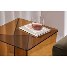 a glass table with a book on it and a drink in the cup sitting on top