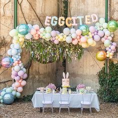 a table set up for an easter party with balloons and bunnies on the wall