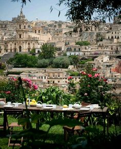 an outdoor table with plates and cups on it in front of a cityscape