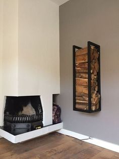 there is a fireplace with logs on the mantle and a firewood rack in the corner