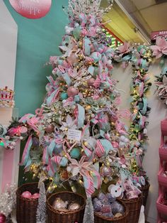 a pink and blue christmas tree with lots of ornaments in baskets on the floor next to it