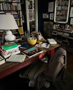 a desk with many books on it and a lamp