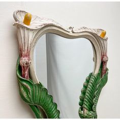 a mirror that is on the wall with some plants in it and two birds perched on top