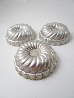 three silver bundt cakes sitting on top of a white table