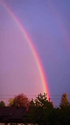 two rainbows are in the sky over some houses