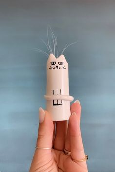 a hand holding a small white tube with a cat on it