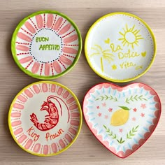 four plates with different designs on them sitting on a table next to each other and one has a heart shaped plate in the middle