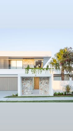 a white house with palm trees in the front yard and two garages on each side