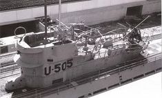 a large boat sitting on top of a train track next to a tall white building