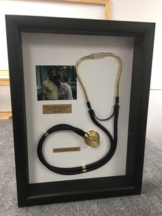 a black and gold framed display with a doctor's stethoscope in it