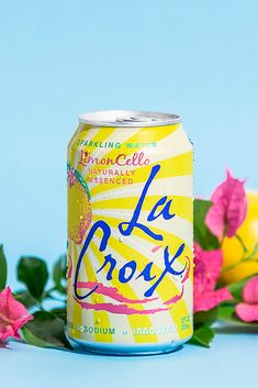 a can of la croix sitting next to some pink flowers on a blue tablecloth