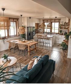 a living room filled with furniture next to a kitchen and dining room table covered in potted plants