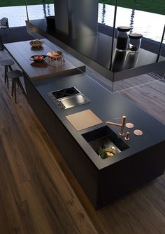 a modern kitchen with black counter tops and wooden flooring