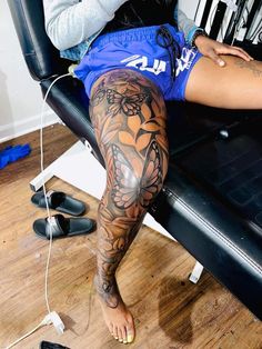 a woman sitting in a chair with tattoos on her legs and leg, next to a hair dryer