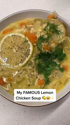 a white bowl filled with soup next to a slice of lemon