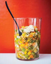 a glass filled with food sitting on top of a table next to a red wall